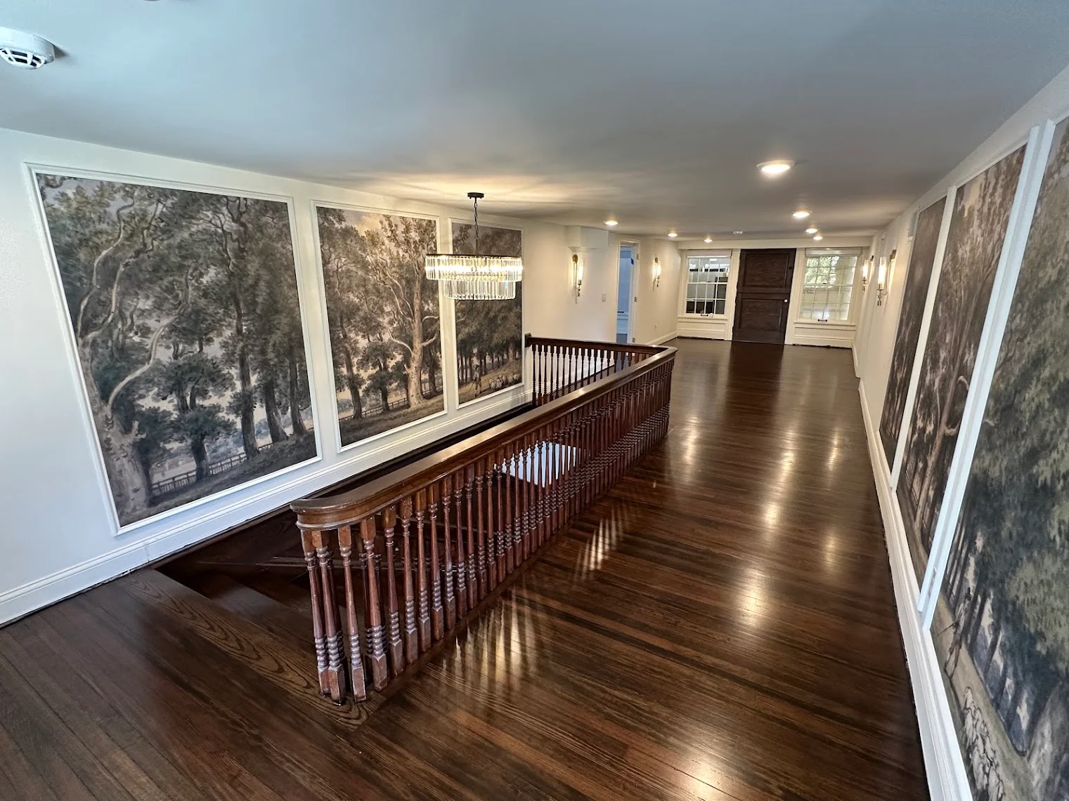 Freshly refinished dark hardwood floor along a Kansas City home's upstairs hallway and staircase landing, the kind of original wood worth checking for sandable life before assuming it needs replacing